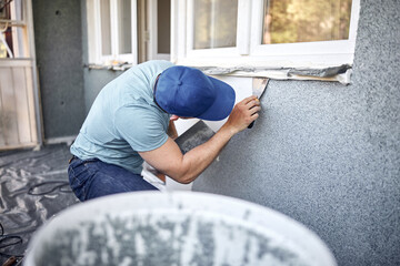 Wall Mural - Man working on a house facade.