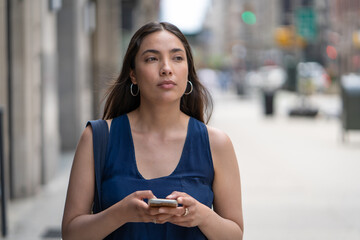 Wall Mural - Young Latina Hispanic woman walking street texting on cellphone