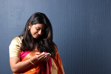 beautiful hindu girl  wearing traditional indian saree dress and ethnic jewelry holding flower.