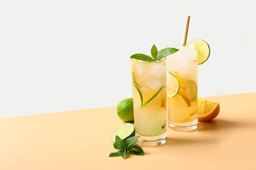 Wall Mural - Two summer cold mojito cocktails with orange and lime slices on color white and beige background. Refreshing summer beverage.