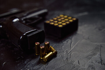 Black pistol with cartridges on table. Automatic firearms with bullets. Weapons on concrete background. Gun for defense or attack.