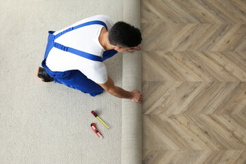 Wall Mural - Worker rolling out new carpet indoors, above view