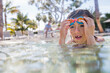 Young boy wearing swimming goggles in pool
