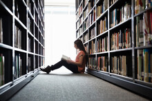 Female Student Sitting On Library Floor At College Campus