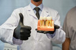 © Kostiantyn - Unrecognised dental technician posing with model of tooth implant