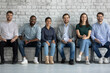 © fizkes - Group portrait of diverse candidates for position in international corporation, sitting on chairs in row, looking at camera, smiling. Queue of confident motivated applicants waiting for job interview.