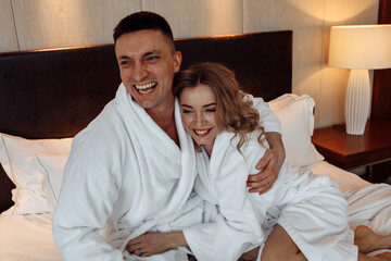 Husband and wife together in a hotel room. Photoshoot of a couple in love in the bedroom. White background.