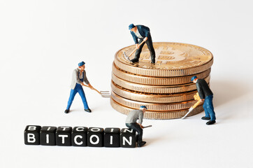 Group of miner figurines with equipment working on stack of bitcoins near black cubes with Bitcoin text. Cryptocurrency, blockchain or trading concept.