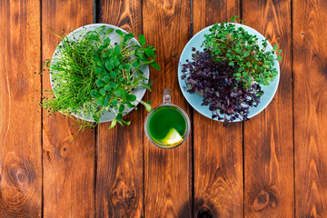 Microgreen mix smoothie and two plates with many different micro greens on a wooden table