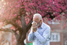 Man With Allergy Symptoms Sneezing Outside In Springtime