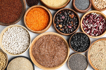 Various raw veggie seeds in bowls on white background, top view