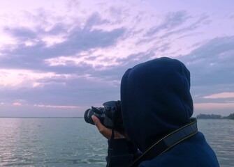 Photographer person taking photos with his camera at sunset. 