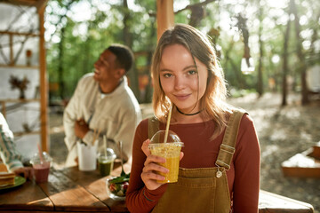 Happy young caucasian woman drinking juice and smiling