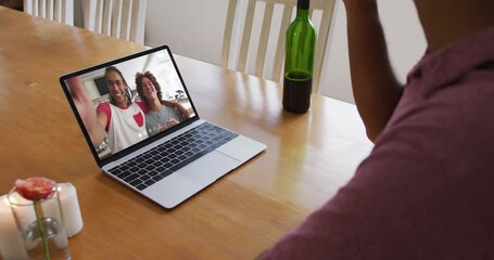 Sticker - Mid section of african american man drinking wine while having a video call on laptop at home