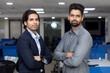 Portrait of two young handsome Indian businessmen standing against office background, corporate environment.