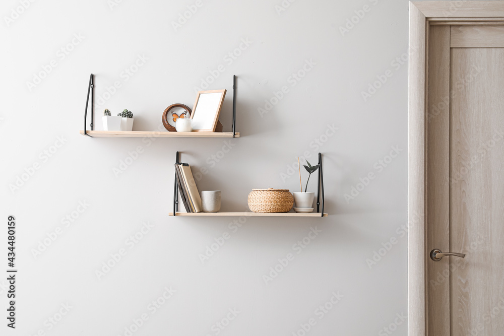 Modern shelves with decor hanging on light wall