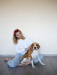 © Aleksandra Iarosh - a young woman combing a beagle dog with a furminator. grooming at home