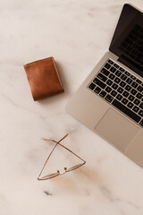 Wall Mural - Home office desk workspace with laptop, glasses, wallet on marble table background. Aesthetic blog, web, social media concept.