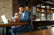 © NDABCREATIVITY - Portrait of a successful business man sitting at the cafe working on a laptop.