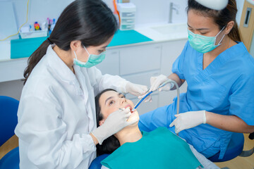 Wall Mural - Dental team wearing face mask providing treatment service in clinic.