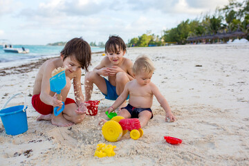 Sticker - Cute baby boy playing with beach toys on tropical beach