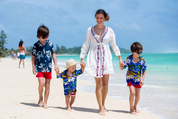 Wall Mural - Mother and children playing at tropical beach. Family sea summer vacation. Mom and kids, boys, play in the water. Ocean and water fun for parent and kids. Fit and healthy family