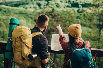 Hikers using map and pointing to the right direction while spending time in nature