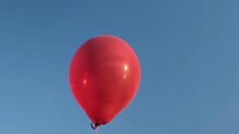 Big Red Hot Air Balloon Flies Against The Blue Sky
