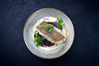Modern style traditional fried skrei cod fish filet with baby broccoli, black red rice in lemon cream sauce served as top view on ceramic design plate with copy space