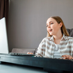 woman learns music singing vocals playing piano online using laptop at home interior. teenager girl 