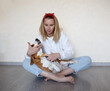 © Aleksandra Iarosh - a young woman combing a beagle dog with a furminator. grooming at home