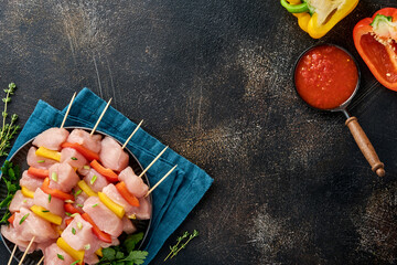 Wall Mural - Raw shish kebab on wooden board, spices, herbs and vegetables on dark grey background. Barbecue Raw ingredients for goulash or shish kebab. Top view. Free copy space.