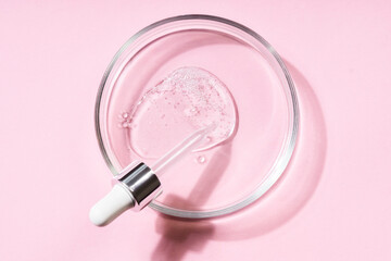 Wall Mural - Pipette with a smear of hyaluronic acid on a round glass support, pink background. Cosmetics concept.