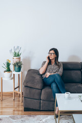 Wall Mural - Beautiful Business Woman Sitting on Sofa and Talking on Mobile Phone
Serious businesswoman relaxing on couch in living room at home and calling somebody on smartphone.