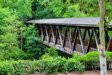 A Long Covered Dark Wood Bridge Over The Big Creek River Surrounded By Lush Green Lush Green Trees At Vickery Creek In Roswell Georgia