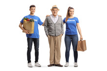 Young Volunteers Helping An Elderly Man With Grocery Shopping Bags