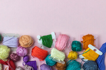 Rolls of thread mulin of different colors on a pink background. Hobbies, embroidery, sewing