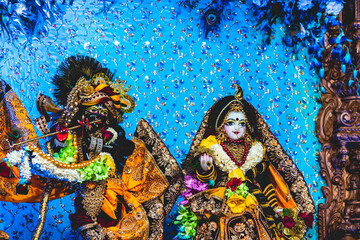 Close up of vibrant and beautiful marble and black stone statue of goddess Radha and Lord krishna decorated with colourful flowers, clothes and precious jewellery at the Indian temple.