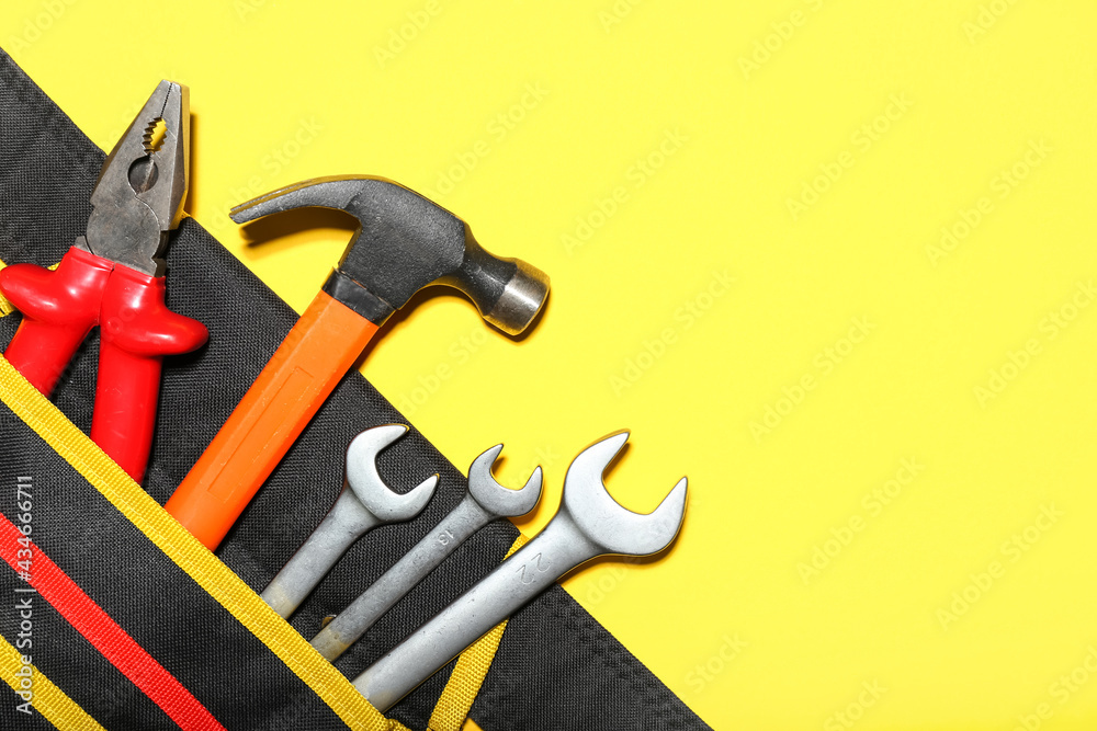Bag with hammer, pliers and wrenches on color background