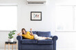 © Pixel-Shot - Young woman with air conditioner remote control at home