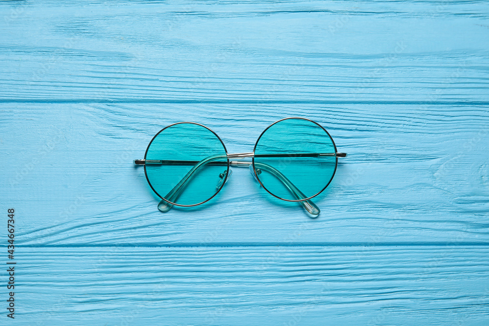 Stylish sunglasses on color wooden background