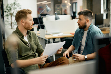 Young male entrepreneurs talking about business reports while working in the office.