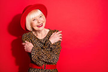 Sticker - Photo of cheerful dreamy nice old woman look empty space hug herself love isolated on red color background