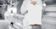 Operator Holds Bag Of Flour With Products In Background Of Automatic Mill For Wheat And Cereals