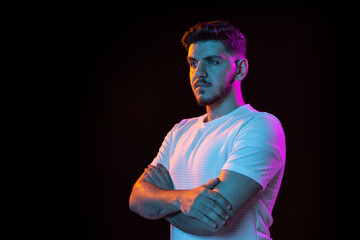young man's portrait on black studio background in neon light. concept of human emotions, facial exp