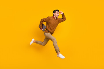 Poster - Full size profile photo of impressed nice brunet man hold laptop run wear sweater isolated on yellow background