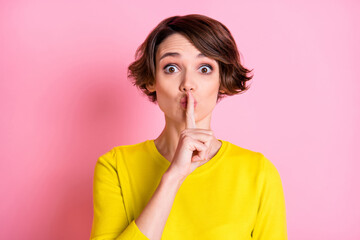 Portrait of attractive funny mysterious brown-haired girl showing shh sign isolated over pink pastel color background