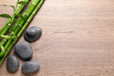 Fototapeta Dziecięca - Spa stones and bamboo stems on wooden table, flat lay. Space for text