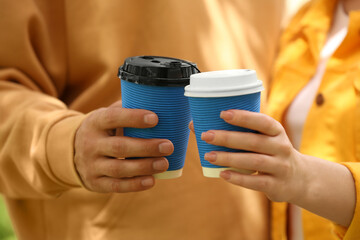 Poster - Couple with takeaway coffee cups outdoors, closeup