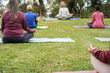 People doing yoga class keeping social distance at city park - Focus on right hand